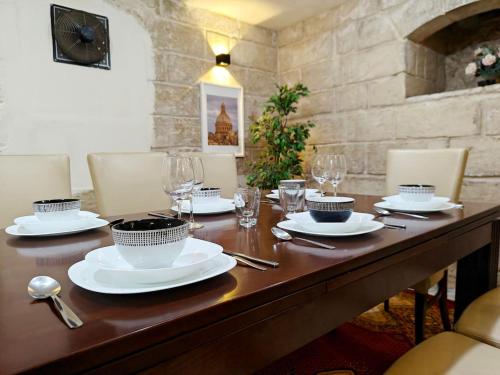 a wooden table with plates and glasses on it at Casa Maltija Sliema 4 Bedroom in Sliema