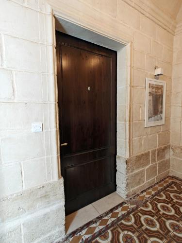 a brown door in a brick wall with a tile floor at Casa Maltija Sliema 4 Bedroom in Sliema