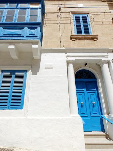 a building with a blue door and two windows at Casa Maltija Sliema 4 Bedroom in Sliema