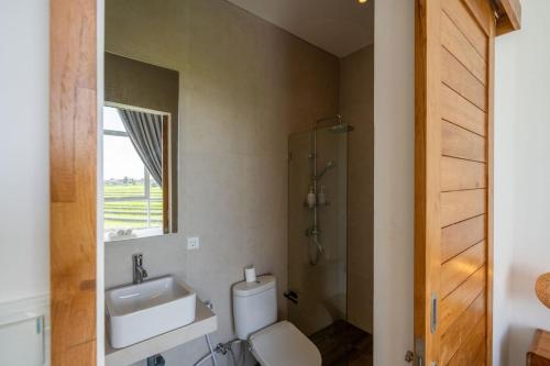 a bathroom with a sink and a toilet and a mirror at Sunrise Bliss 13 Ricefield View Private Pool Villa By Bali Bliss Properties in Dalung