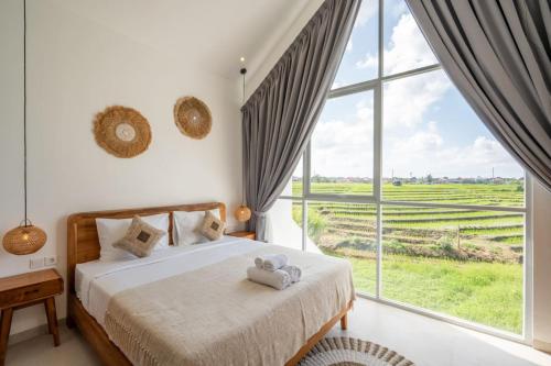 a bedroom with a bed and a large window at Sunrise Bliss 13 Ricefield View Private Pool Villa By Bali Bliss Properties in Dalung