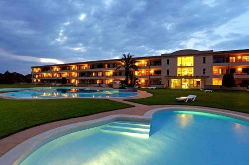 a hotel with two pools in front of a building at Apart-Hotel Golf Beach 35201 in Sa-Riera