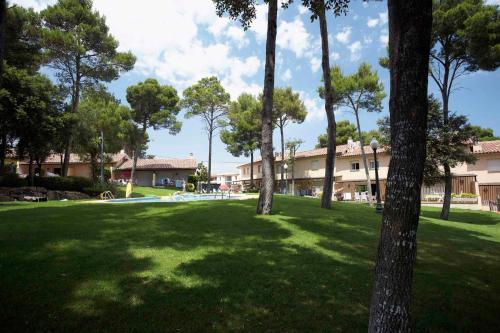 a park with trees and a building in the background at Apart-Hotel Golf Beach 35201 in Sa-Riera