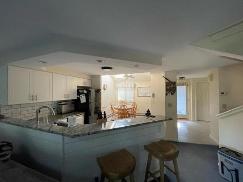 a kitchen with a counter and some chairs in it at 3BR Lake Winnipesaukee Condo with Sandy Beach in Laconia