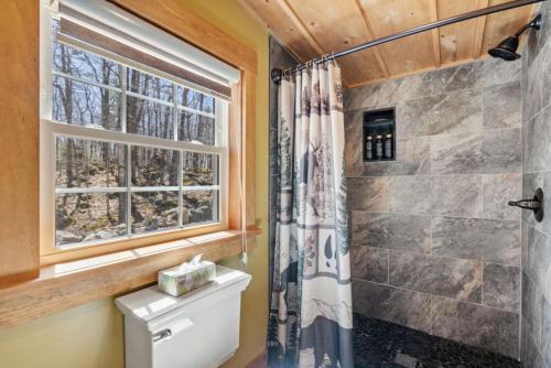a bathroom with a shower and a toilet and a window at Cozy 3BR with Firepit and Boat Slip Option in Moultonborough