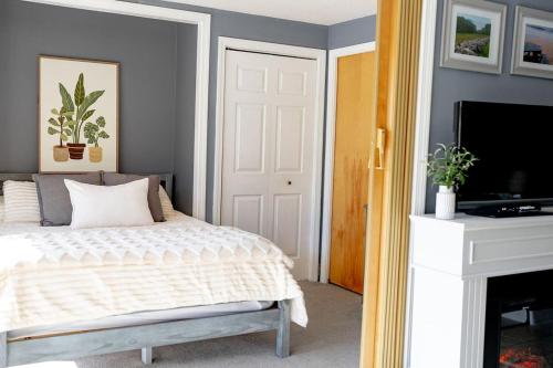 Un dormitorio con una cama y un televisor de pantalla plana. en The Cozy Cove - Walk to Concerts & Lake, en Gilford