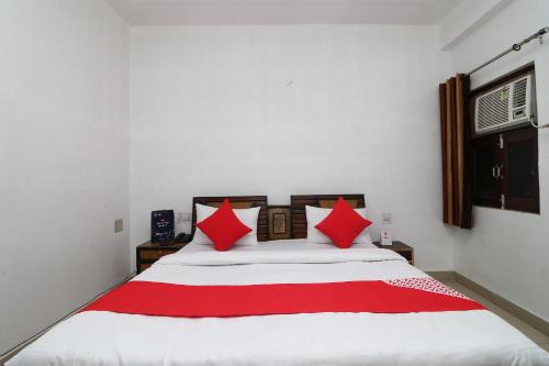 a bedroom with a large bed with red pillows at Four Seasons in Sikandra