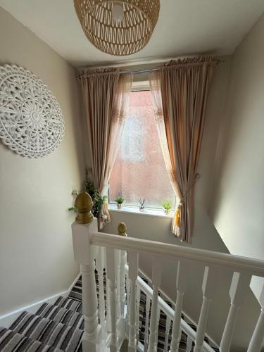 a stairway with a window with curtains and a white railing at Room at quiet location close to Belfast in Carnmoney