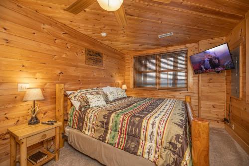 ein Schlafzimmer mit einem Bett in einer Blockhütte in der Unterkunft Heavenly Homestead by American Patriot Getaways in Park Settlement