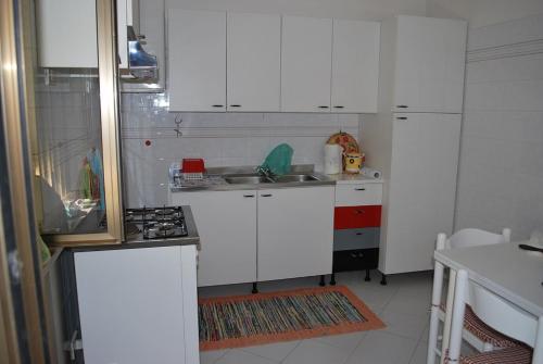 uma pequena cozinha com armários brancos e um lavatório em Marche Hills em Morrovalle