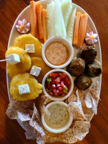 a plate of food with appetizers and dips on a table at Monkey House Hostel in Tola