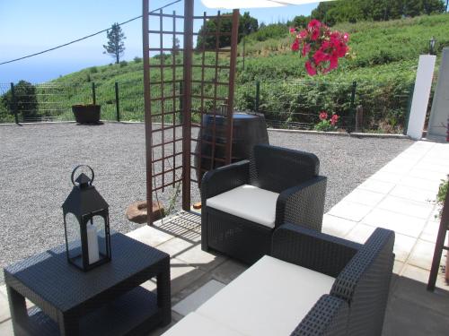 a patio with two chairs and a table and a lamp at Casa Formiga in Fajã da Ovelha