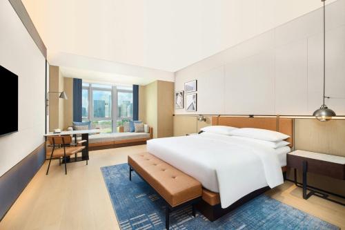 a bedroom with a large white bed and a desk at Four Points by Sheraton Nanning, Wuxiang in Nanning