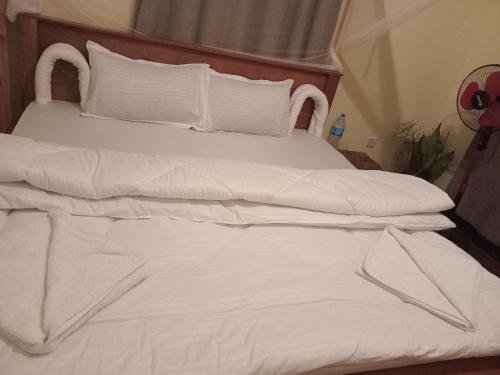 a white bed with white sheets and pillows at Patience Airport cottages in Boma la Ngombe