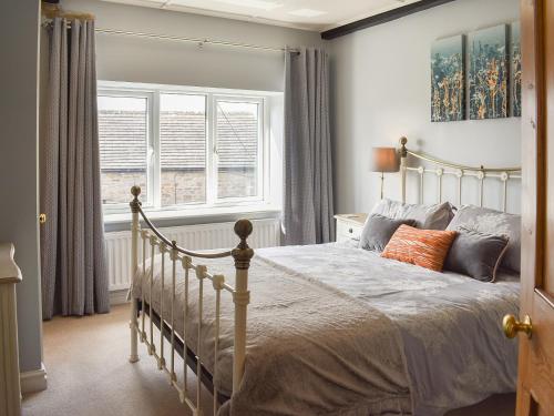 a bedroom with a white bed and two windows at 3 Winville Mews in Askrigg