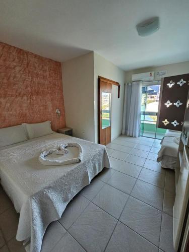 a bedroom with a bed with a white bedspread at Hotel Cores do Mar in Bombinhas