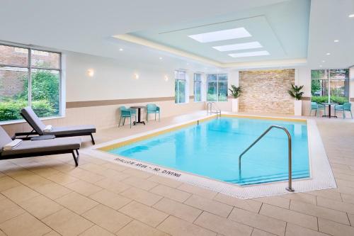 a large swimming pool in a waiting room with chairs and tables at TownePlace Suites by Marriott Mississauga-Airport Corporate Centre in Mississauga