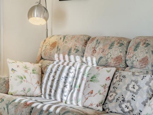 a couch with pillows on it in a living room at Rose Cottage in Pembrey