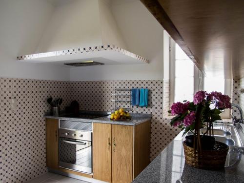 a kitchen with a sink and a counter with purple flowers at Casa do Souto in Aldreu