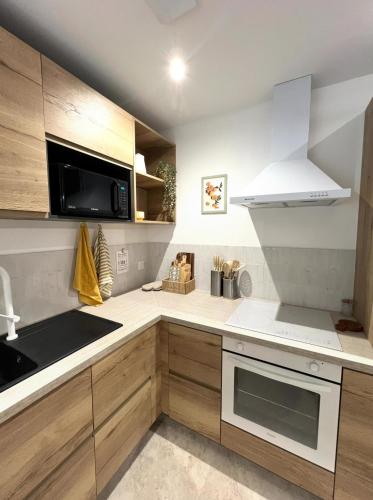 a kitchen with white appliances and wooden cabinets at Serenity Appart', Les Clés de l'Espoir, proche Poitiers in Nieuil-lʼEspoir