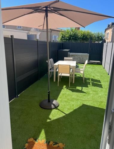 an umbrella on a lawn with a table and chairs at Serenity Appart', Les Clés de l'Espoir, proche Poitiers in Nieuil-lʼEspoir