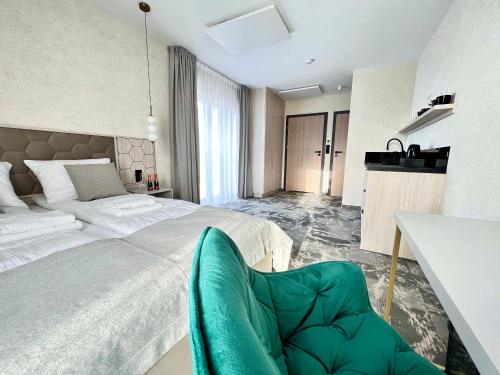 a bedroom with a large bed and a green chair at SILVER BALTIC in Kołobrzeg