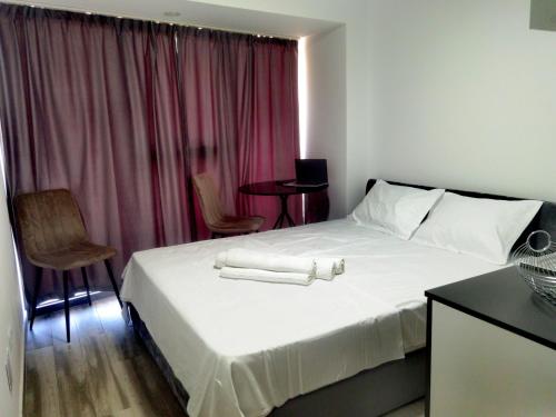 a bedroom with a white bed with a pink curtain at Studio Olimp Sea View Apartments in Olimp
