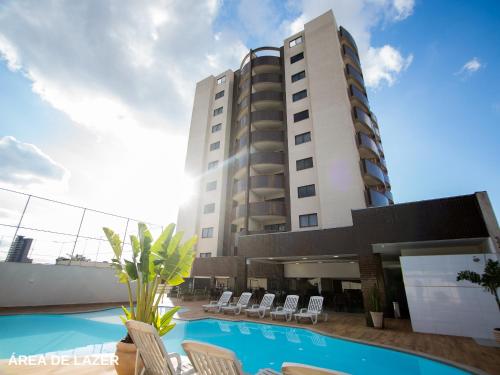 a hotel with a swimming pool in front of a building at ApartDamani - Aptos por Temporada no centro in Foz do Iguaçu
