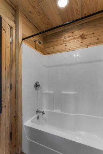 a white tub in a bathroom with a wooden ceiling at Mr Hills Mercantile Cabin with a hot tub in Bryant
