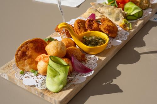 a plate of food on a wooden board with food at Canella Beach Hotel in Le Gosier