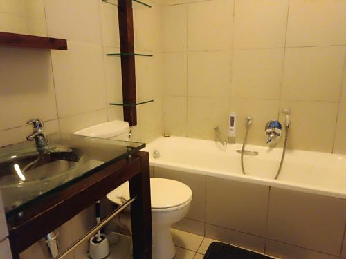 a bathroom with a toilet and a tub and a sink at Malaika Luxurious Crib, Jackal Creek Golf Estate, Northriding in Roodepoort