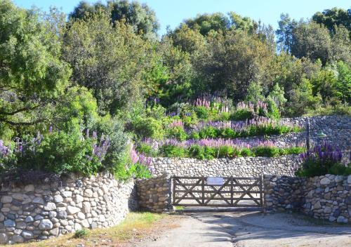 a gate in a stone wall with purple flowers at Aparts La Balconada by DOT Suites in Villa Pehuenia
