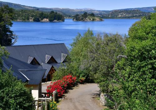 a house on the shore of a lake with flowers at Aparts La Balconada by DOT Suites in Villa Pehuenia