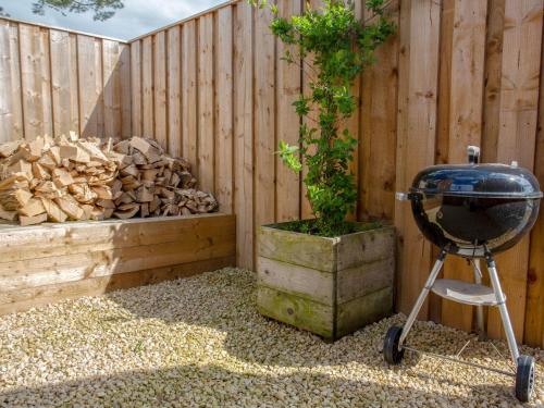 a grill and a tree in a barrel next to a fence at Brens Barn in Bedale