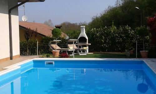 a blue swimming pool with a table and chairs next to a house at Villa Panoramica in Pozzolengo