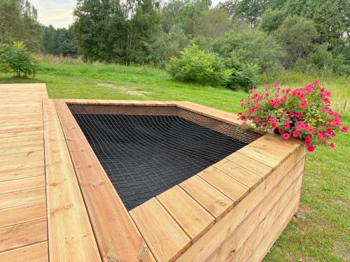 a raised wooden deck with a flower box with flowers at Rātes Krasti - Rasa - holiday house with sauna and lakeview in Lejasciems