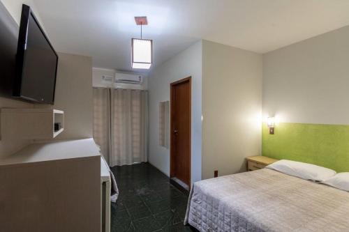a hotel room with a bed and a flat screen tv at Hotel Cores do Mar in Bombinhas