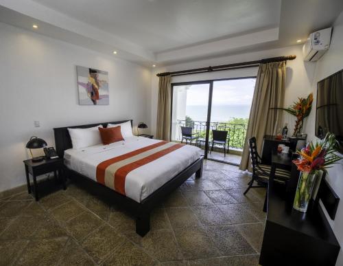 a bedroom with a bed and a desk and a window at Shana by the Beach Manuel Antonio in Manuel Antonio