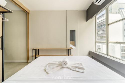 a bedroom with a white bed with a bow on it at Aptos modernos no centro de Floripa - VLR in Florianópolis