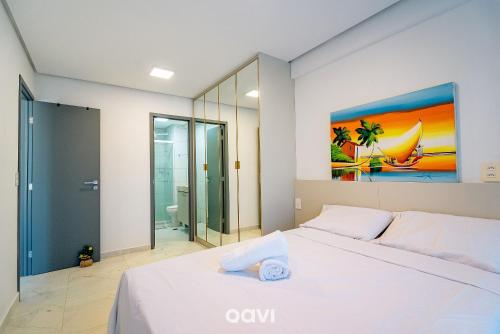 a bedroom with a white bed and a painting on the wall at Flats Confortáveis em Manaíra Mindset - Qavi in Tambaú