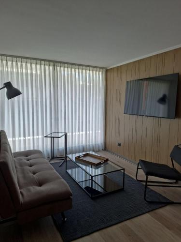 a living room with a couch and a glass coffee table at NM Departamentos Amoblados in Concepción