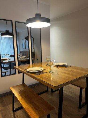a wooden dining table with glasses and a light at NM Departamentos Amoblados in Concepción