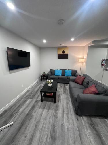 a living room with a couch and a flat screen tv at Elegant Cozy Private Apartment in Calgary