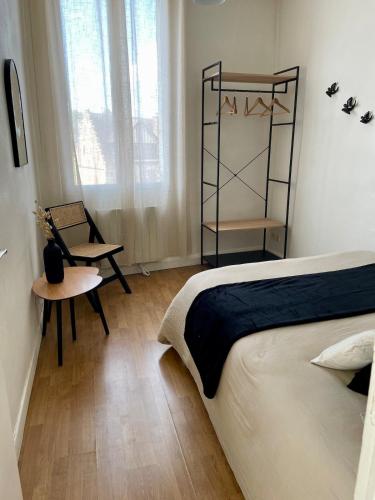 a bedroom with a bed and a chair and a table at L'escapade de saint Antoine in Compiègne