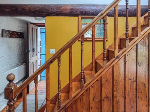 a wooden staircase in a house with a yellow wall at Ceiliog Bach in Llangennith