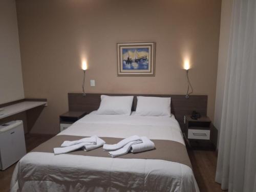 a bedroom with a bed with two white towels on it at Hotel Itapema in Valinhos