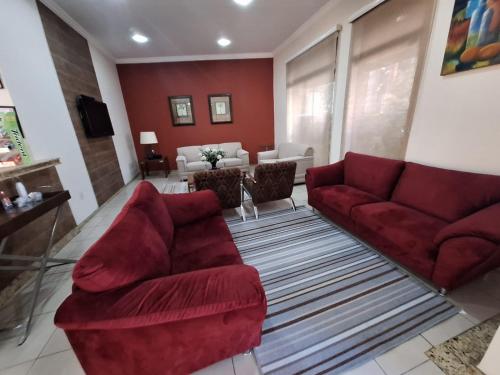 a living room with two red couches and a living room with at Hotel Itapema in Valinhos