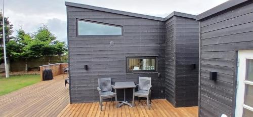 a building with a table and chairs on a deck at Blokhus - tæt på by og strand in Blokhus