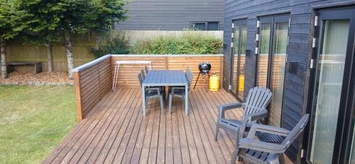 a wooden deck with a table and chairs on it at Blokhus - tæt på by og strand in Blokhus