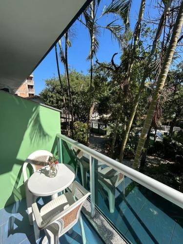 a balcony with a table and chairs and palm trees at Hotel Cores do Mar in Bombinhas